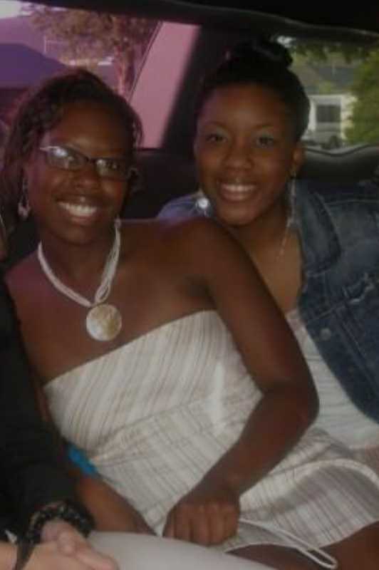 Two young women sitting next to each other, posing for a picture inside of a limousine