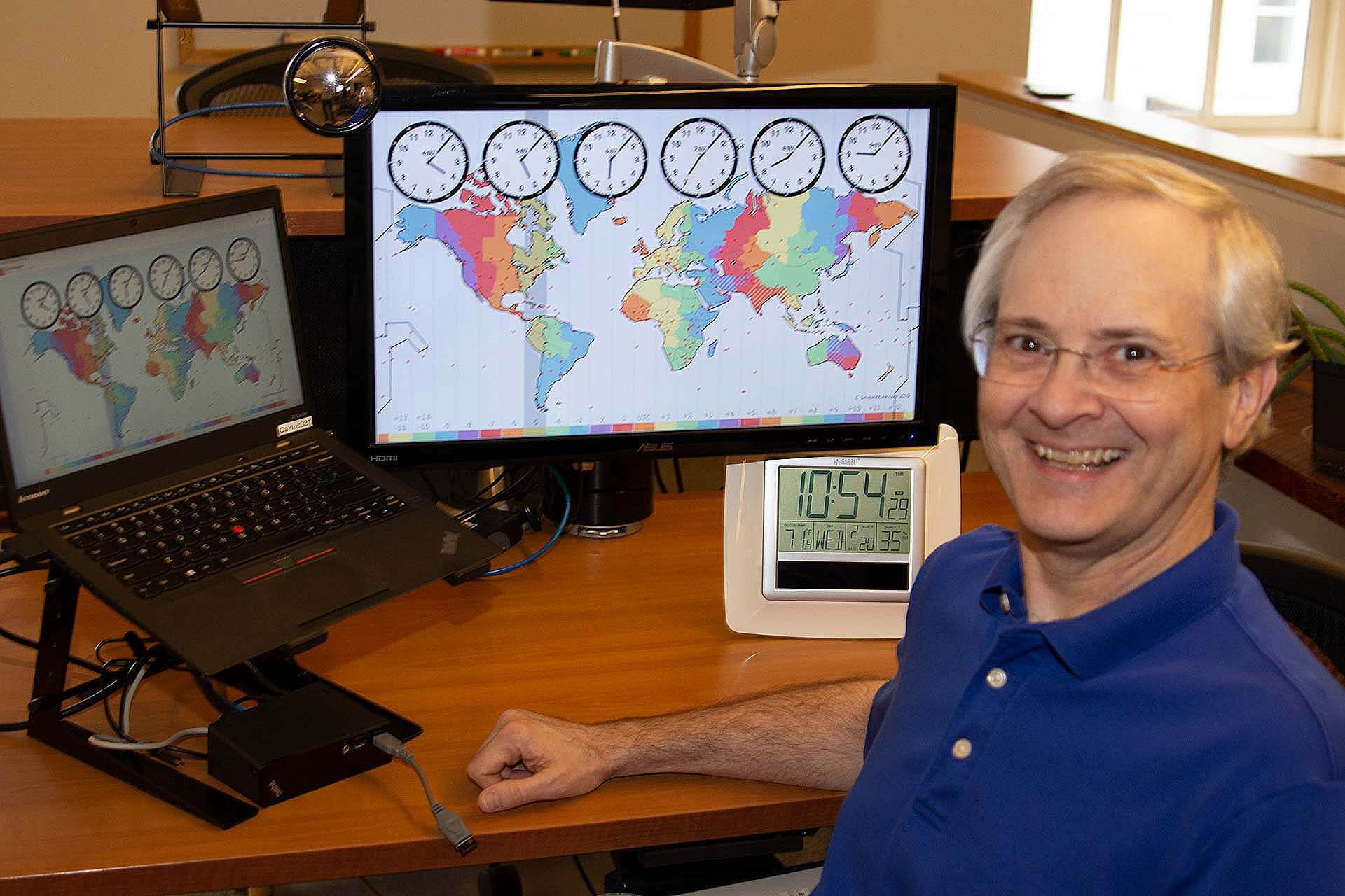 Developer and blog author Dan Poirier at his desk, with a graphic of timezones on his screen.