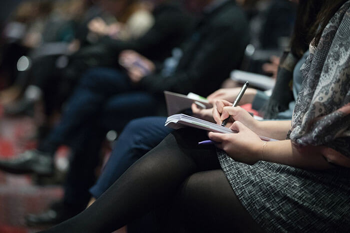 People sitting in a row, taking notes on notebooks