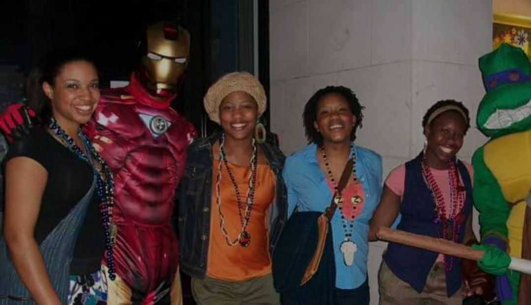 Four young women smiling and posing with Iron Man and Teenage Mutant Ninja Turtle, Donatello.