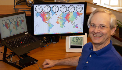 Developer and blog author Dan Poirier at his desk, with a graphic of timezones on his screen.